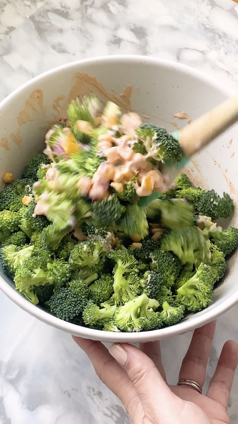 Corn is mixed into broccoli in a bowl.