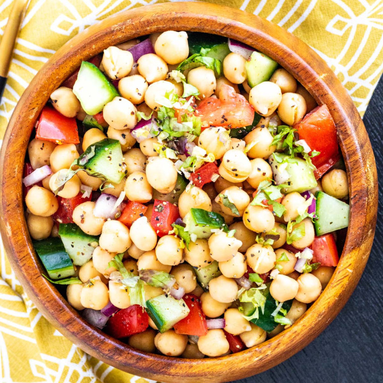A salad with chickpeas, tomatoes, and cucumbers in a wooden bowl.