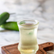 Simple syrup in a small glass jar with jalapenos in the background and text title for Pinterest.