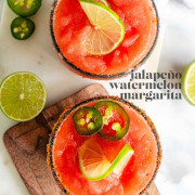A red margarita in a rimmed glass with jalapeno and lime slices on top with a text title for Pinterest.