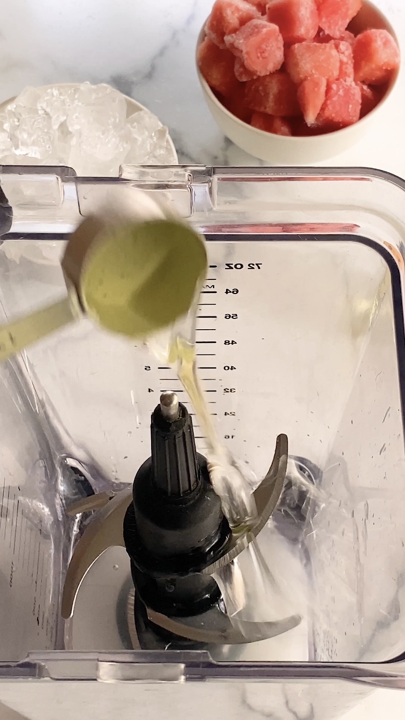 Simple syrup is poured into a blender.