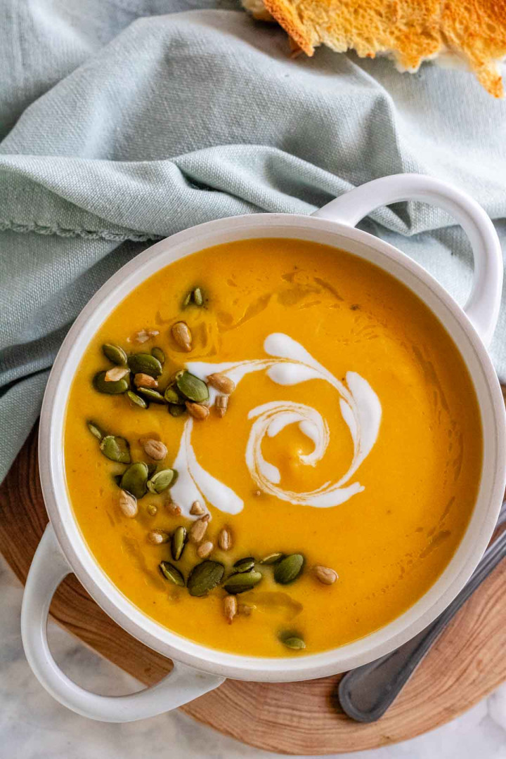 A bowl of soup with a heart shaped coconut milk swirl and seeds on top.