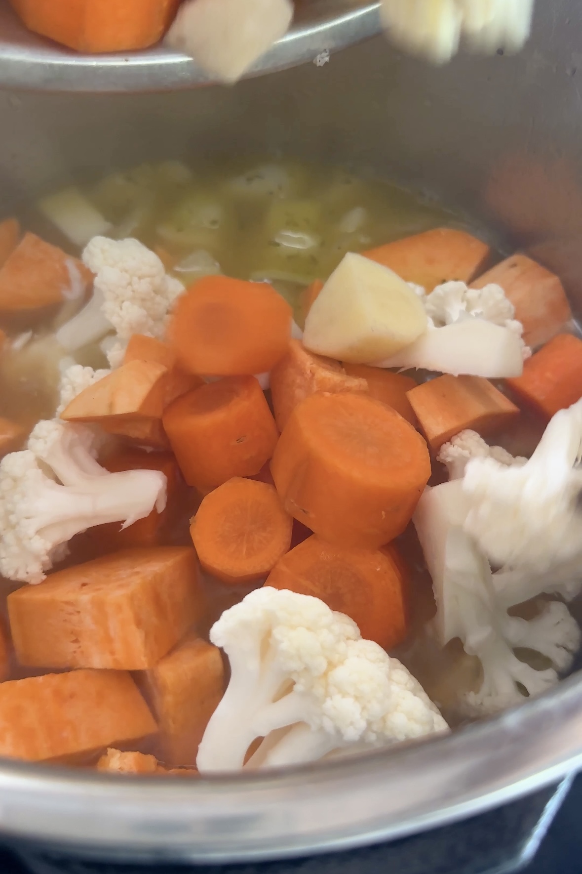 Chopped vegetables are added to an instant pot.