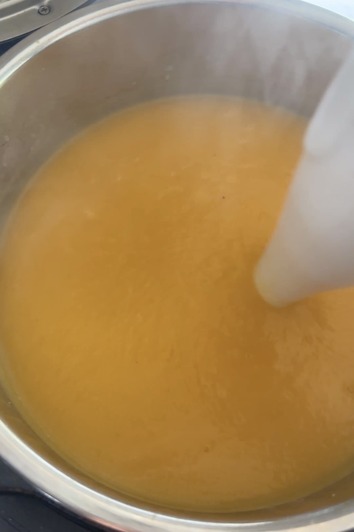 An orange pureed soup is blended.