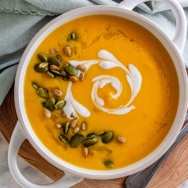 A bowl of soup with a heart shaped coconut milk swirl and seeds on top.