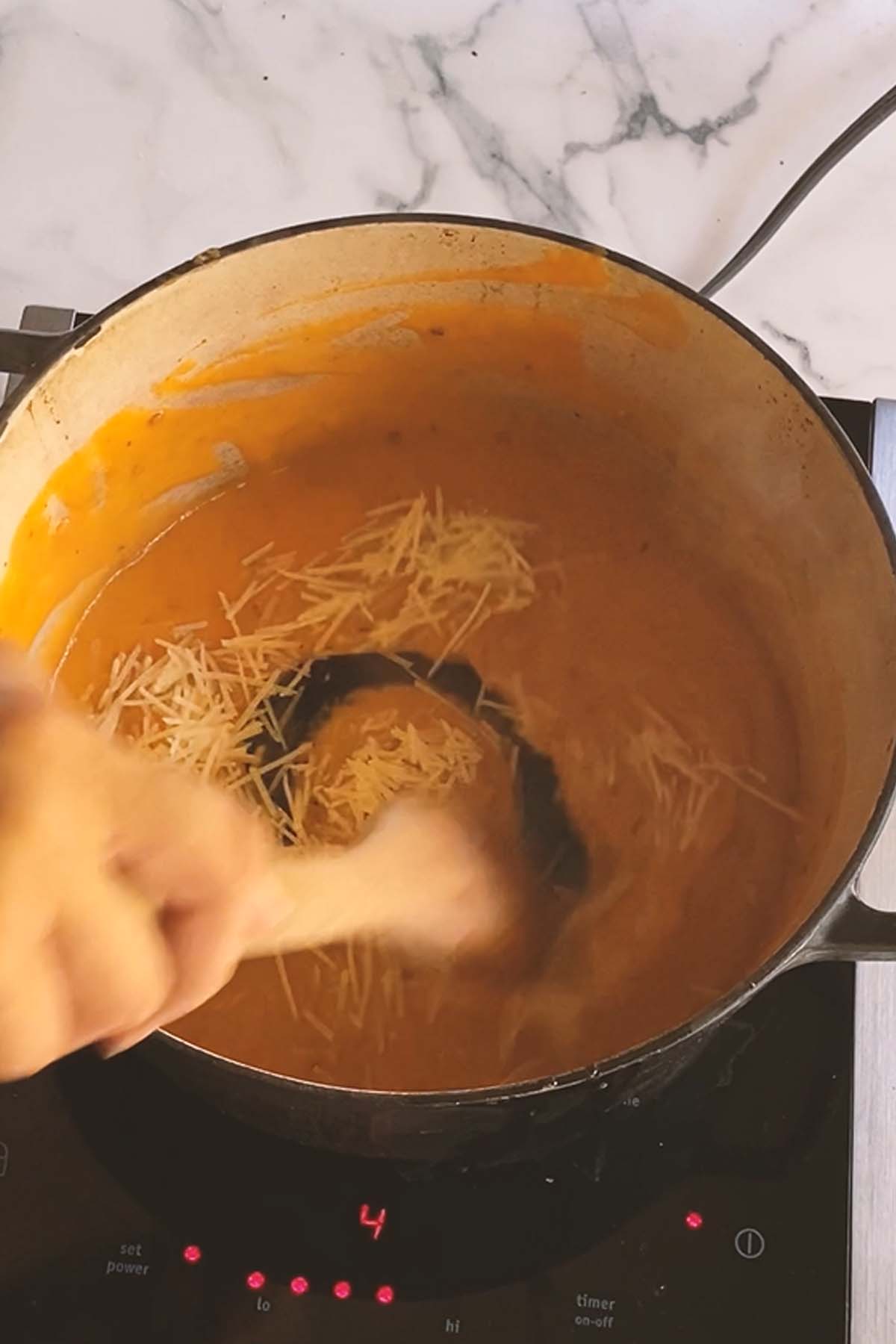 Cheese is stirred into an orange pasta sauce.