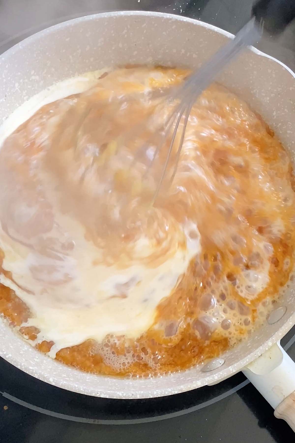Cream is stirred into caramel sauce.