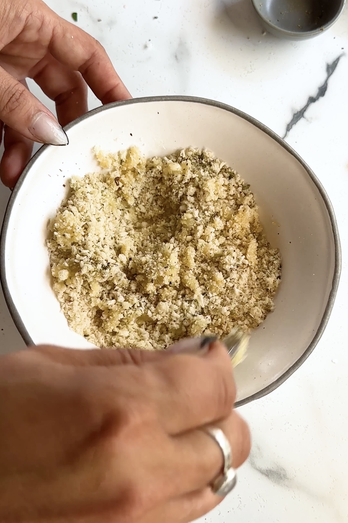 Bread crumbs and butter are stirred together.