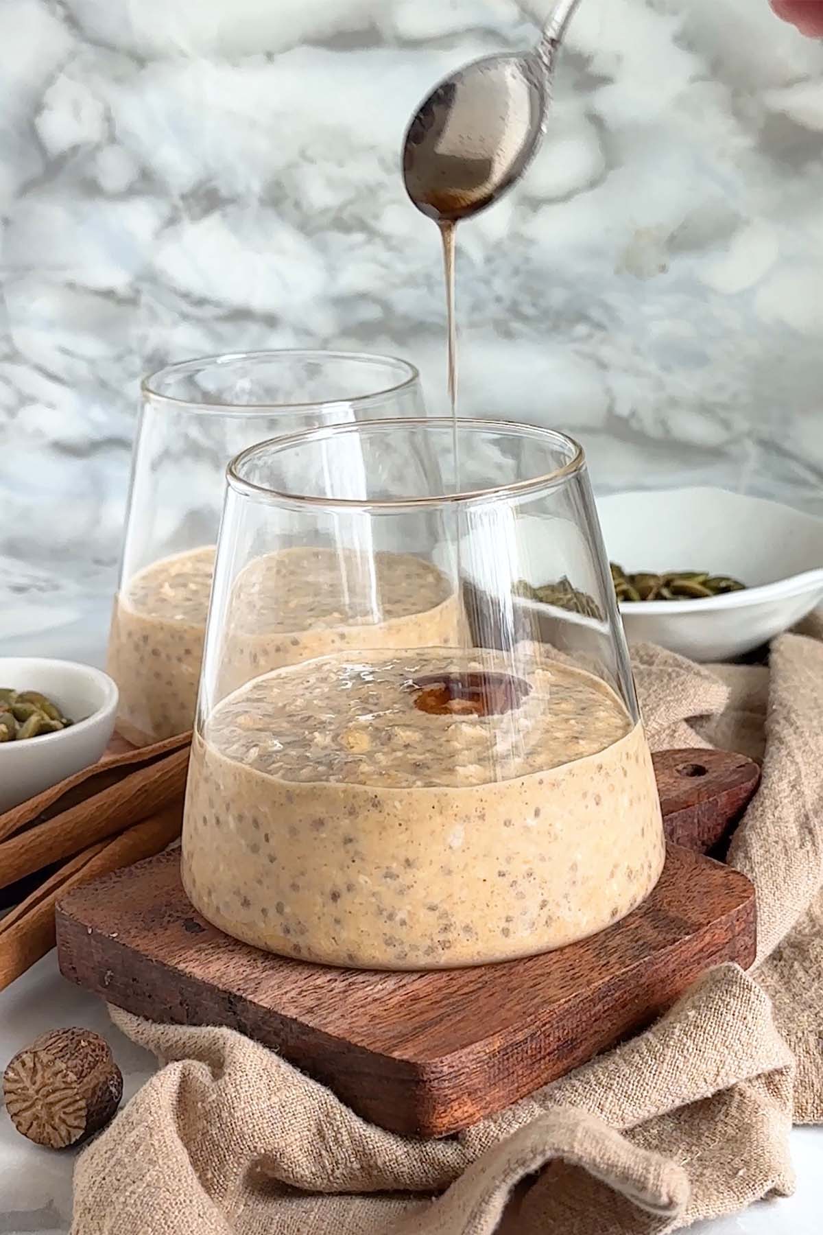 Syrup is added to oats in a glass cup.