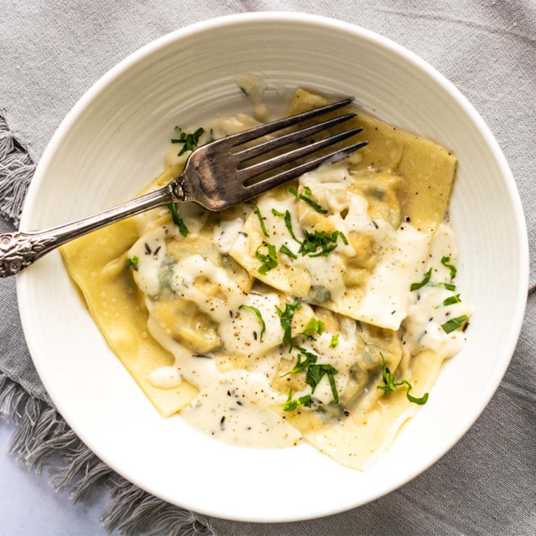 Ravioli in a bowl covered in cream sauce.