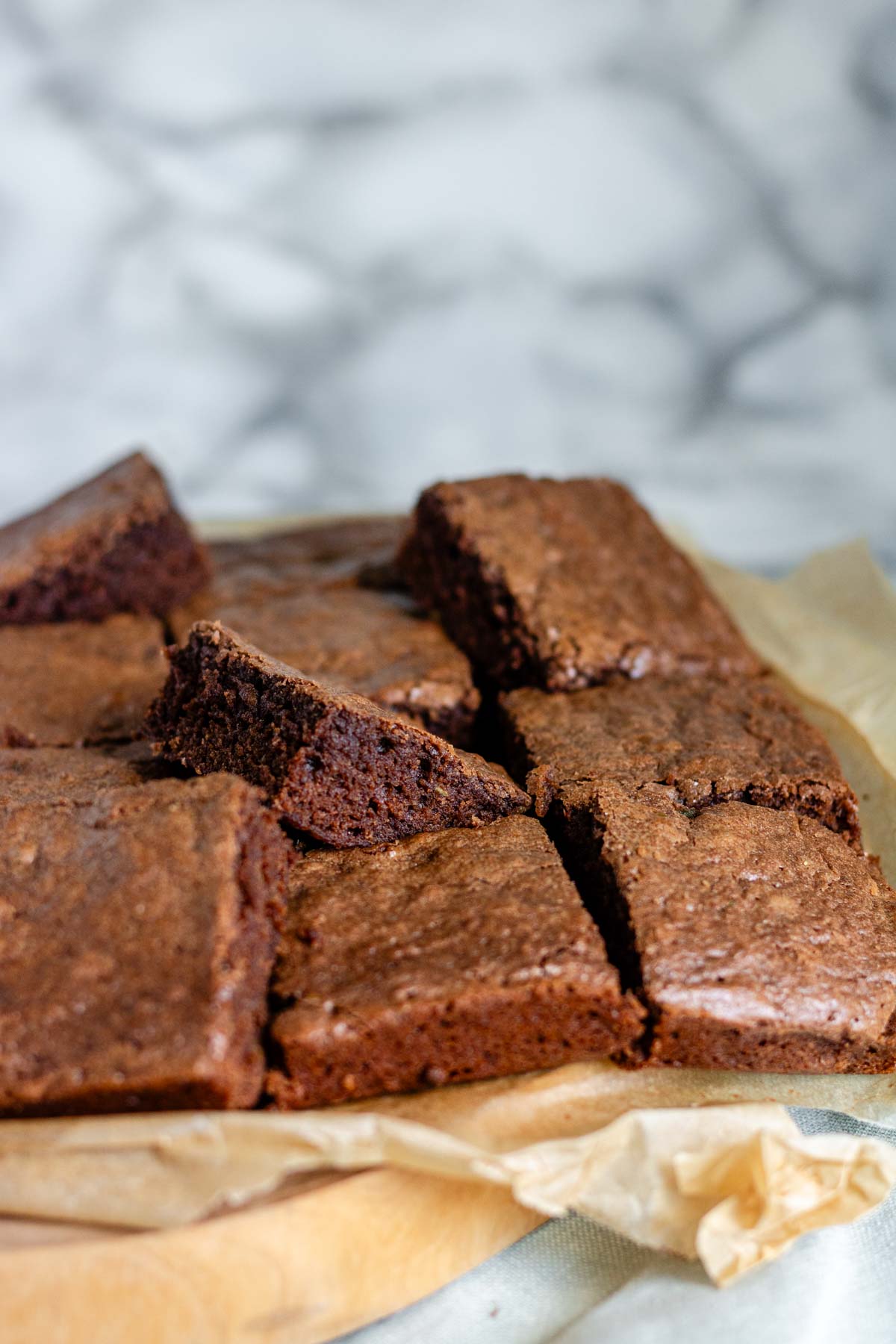 Brownies sit on parchment paper, cut into 16 squares.