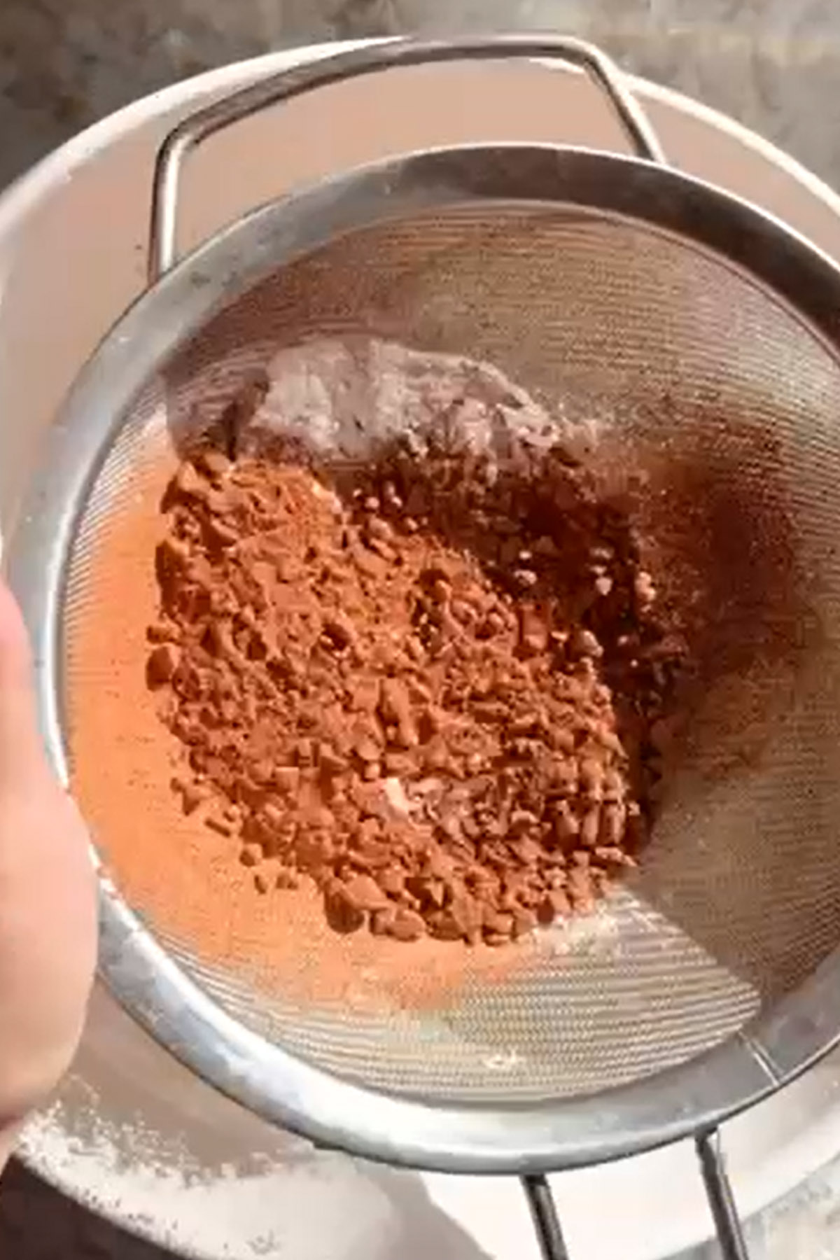 Cocoa powder is sifted in a bowl.