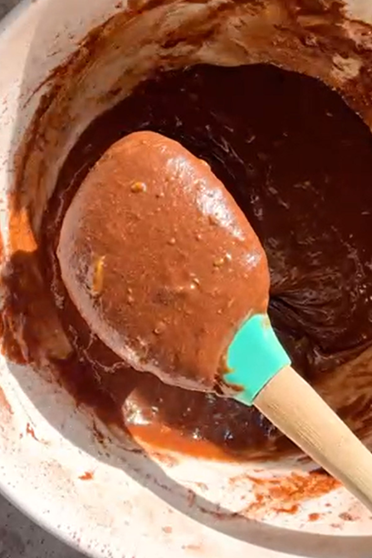 Brownie batter is lifted on a spatula to show texture.