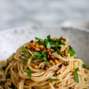 Pasta with brown butter, walnuts, and parsley in a white and black speckled bowl with text title for Pinterest.