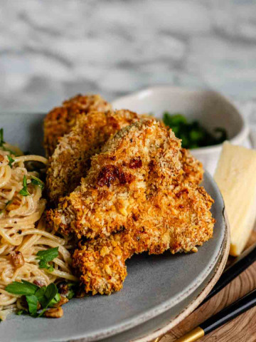 Crispy chicken strips on a plate with pasta.