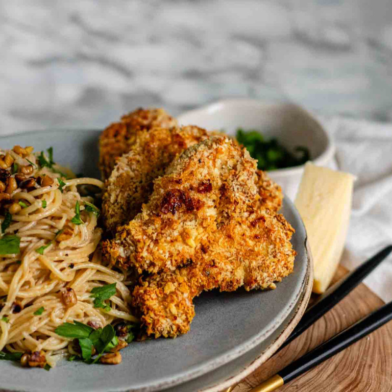 Crispy chicken strips on a plate with pasta.