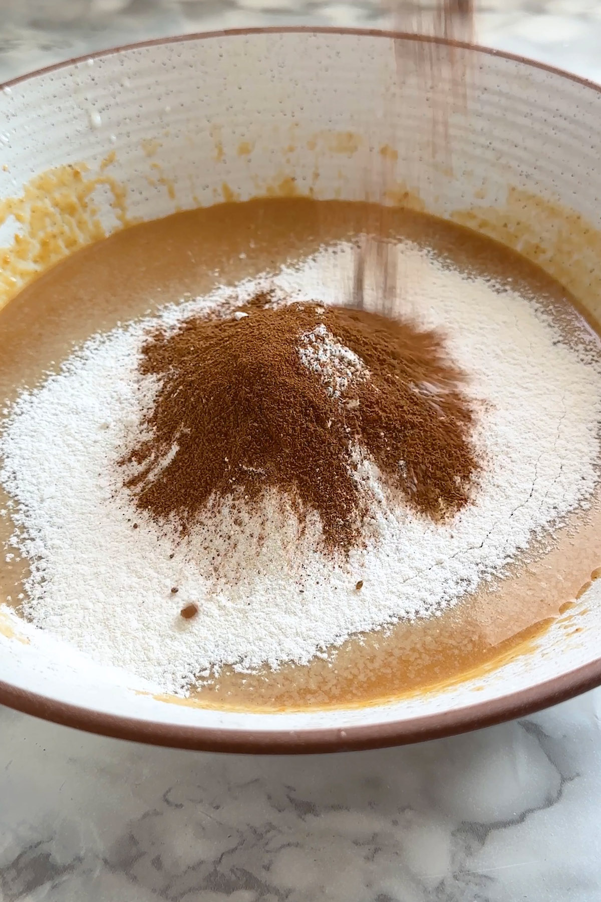 Flour and pumpkin pie spice sit on top of wet ingredients for pancake mix.