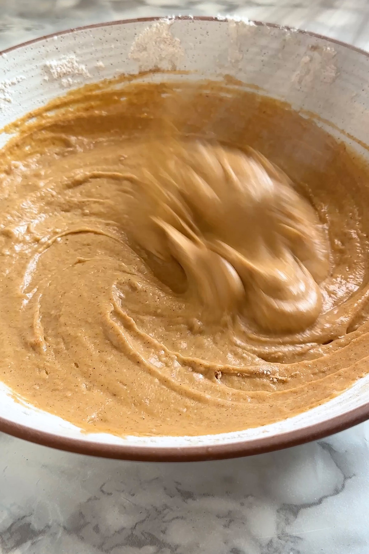 Pancake batter is whisked in a bowl.