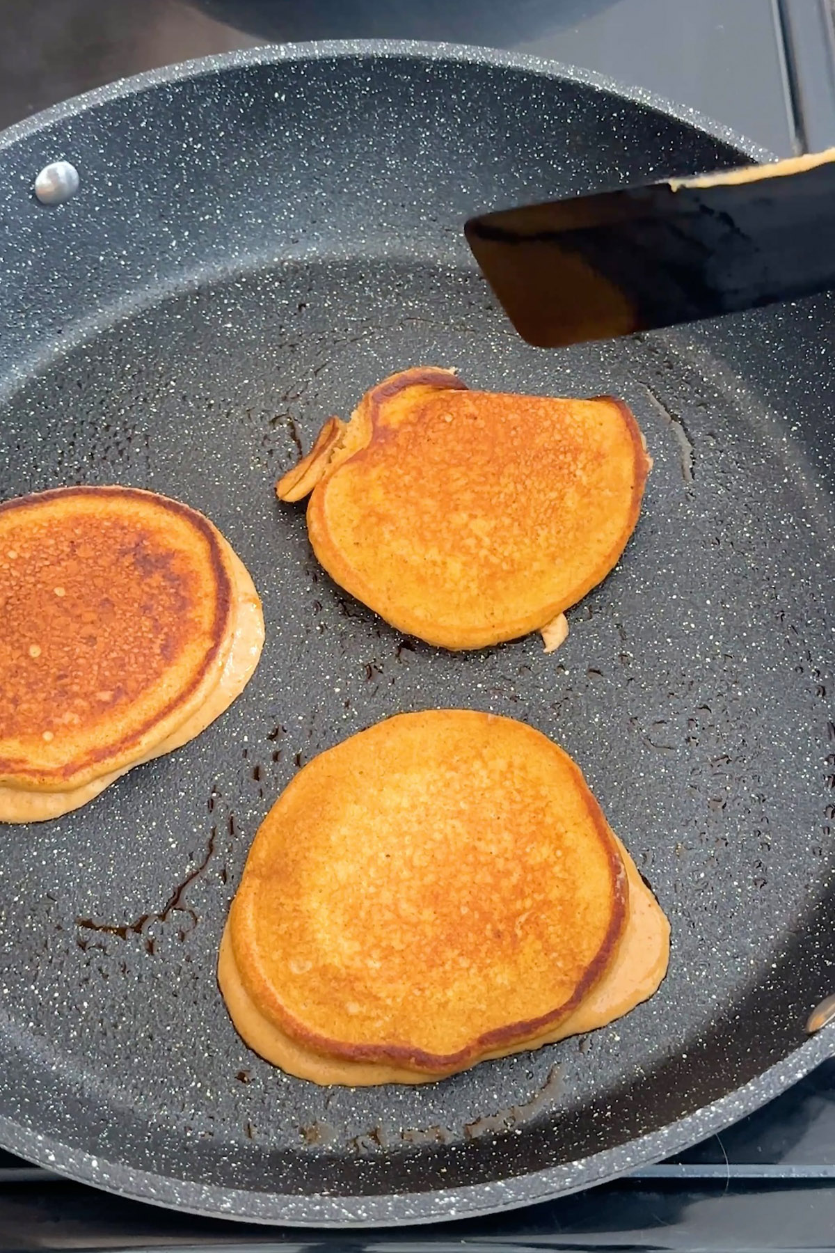 Pancakes are cooked in a skillet.