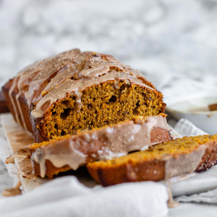 Pumpkin bread on a white marble background with a maple glaze.