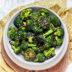Broccoli in a bowl with sesame seeds and red pepper flakes on top.