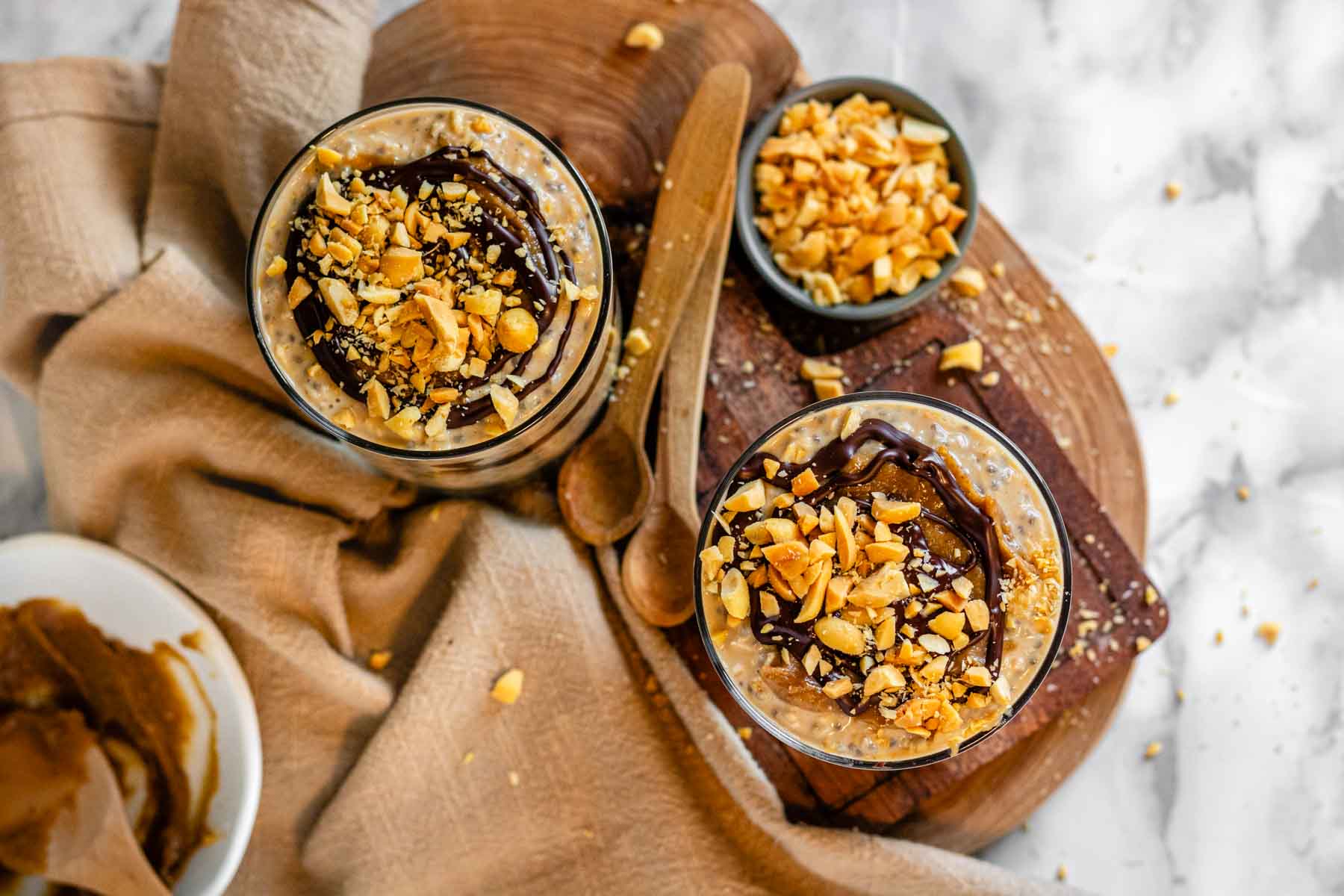 Oats in a glass topped with caramel, chocolate, and peanuts.