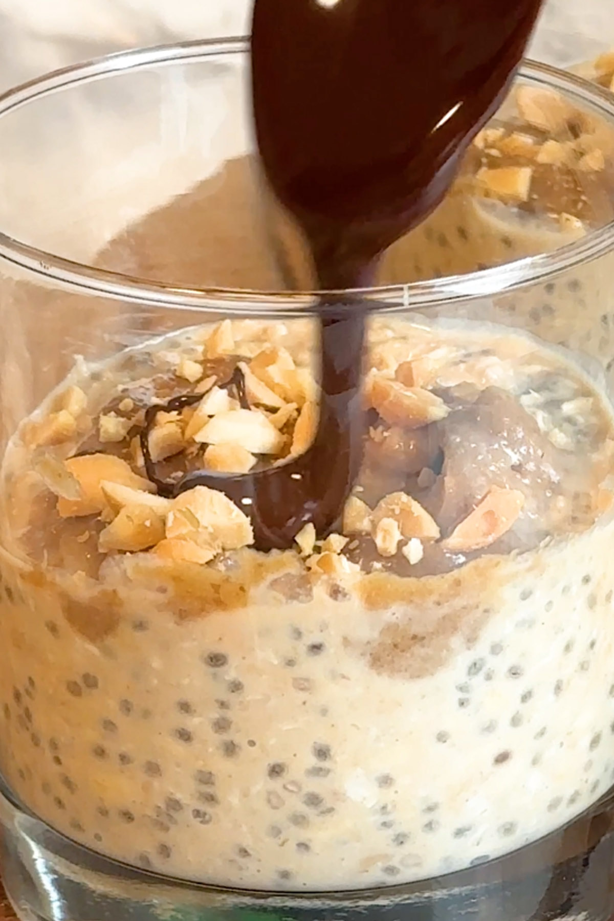 Chocolate is drizzled on top of oats in a glass.
