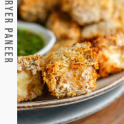 Breaded cubes of paneer on a plate with a green chimichurri sauce with text title for Pinterest.