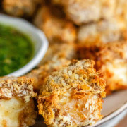 Breaded cubes of paneer on a plate with a green chimichurri sauce with text title for Pinterest.