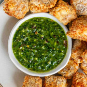 Breaded cubes of paneer on a plate with a green chimichurri sauce with text title for Pinterest.