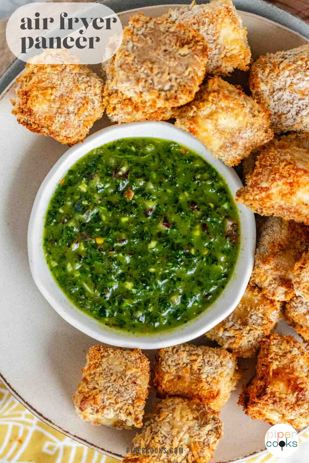 Breaded cubes of paneer on a plate with a green chimichurri sauce with text title for Pinterest.