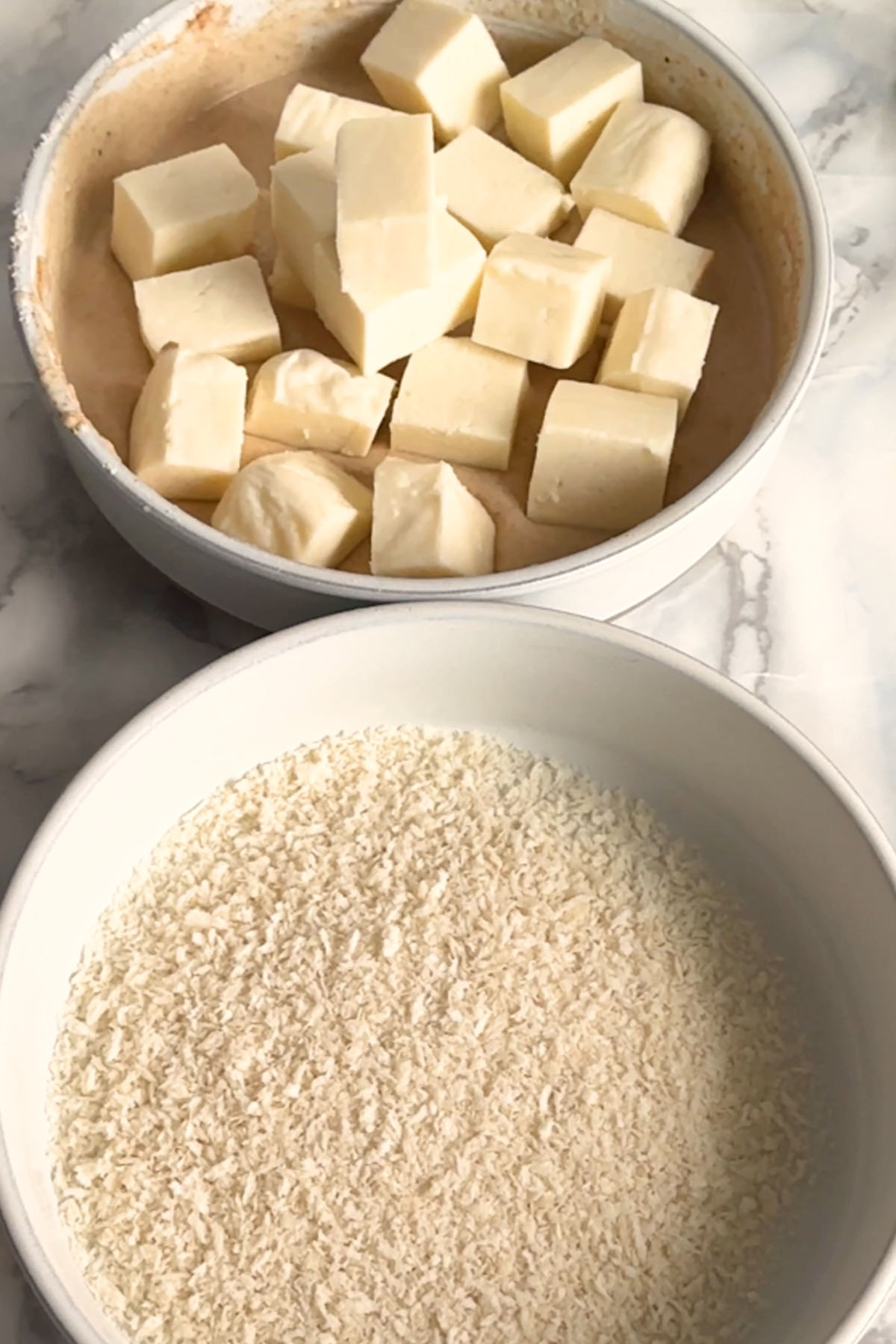 Cubes of paneer sit in a bowl of batter.