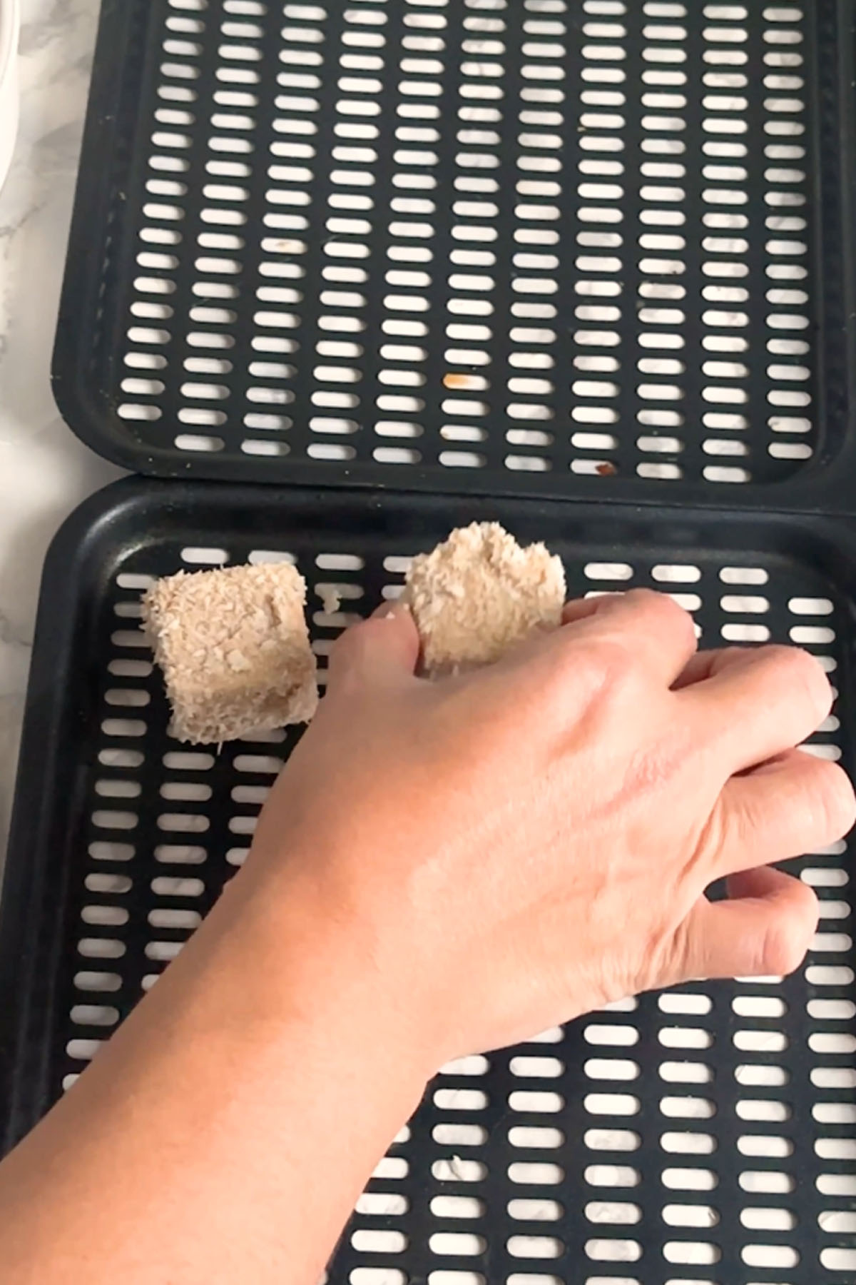 A breaded cube of paneer is placed on a baking tray.