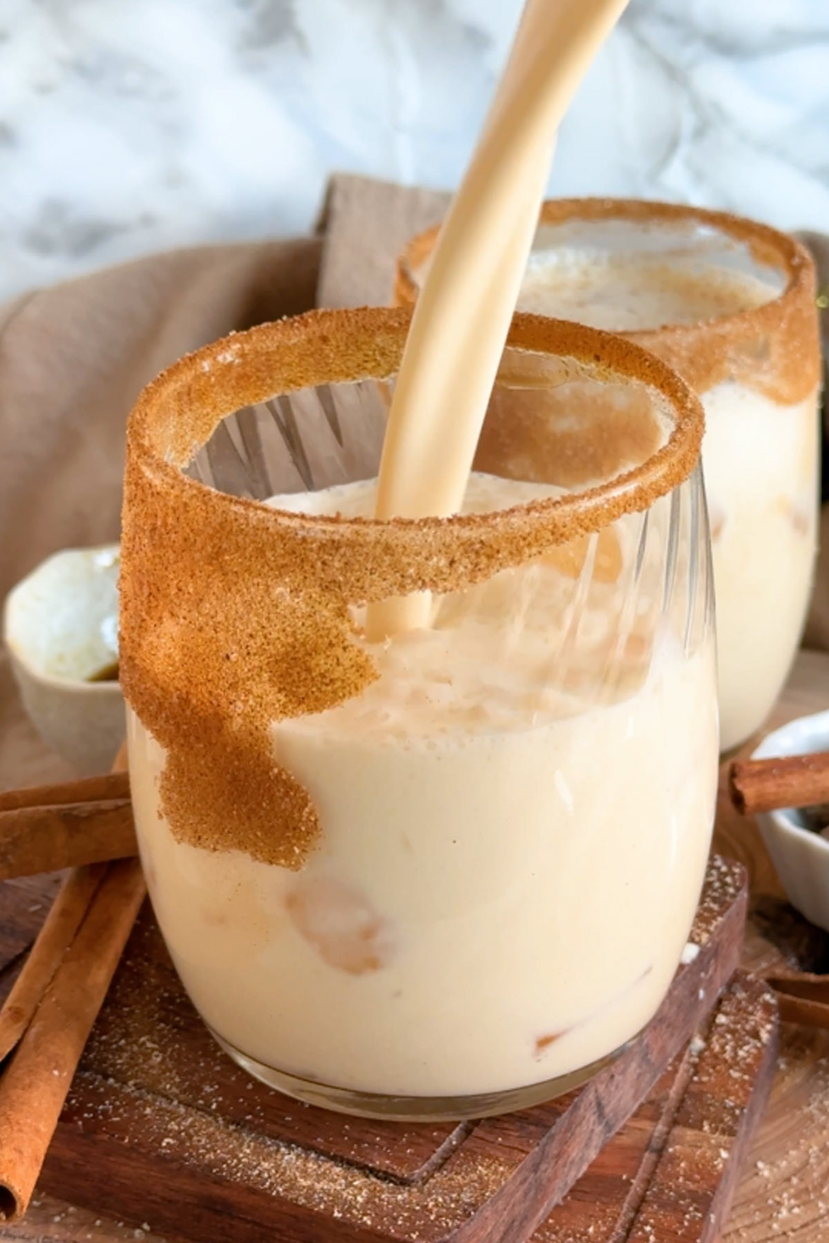 Eggnog is poured into a glass rimmed with cinnamon sugar.