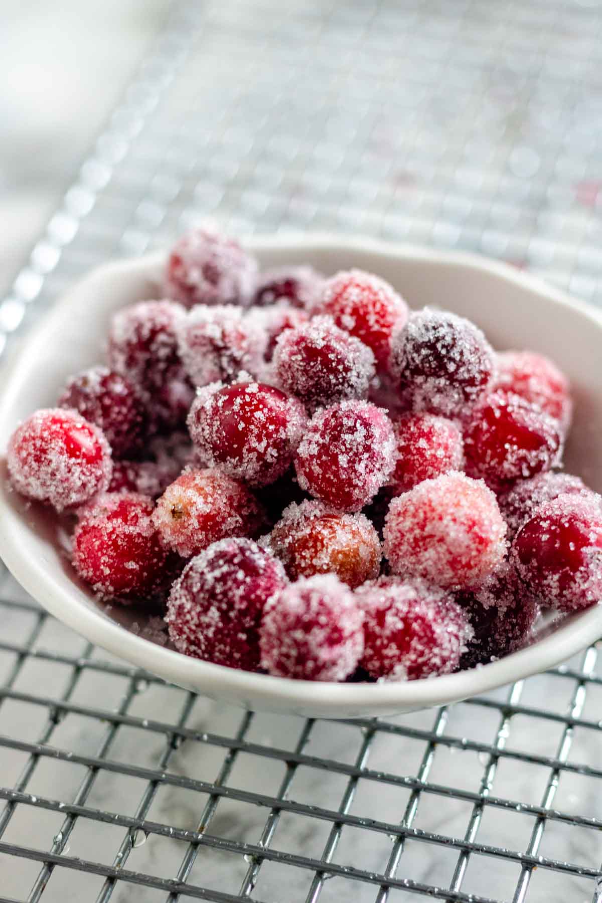 A bowl with sugared cranberries on a wire rack.
