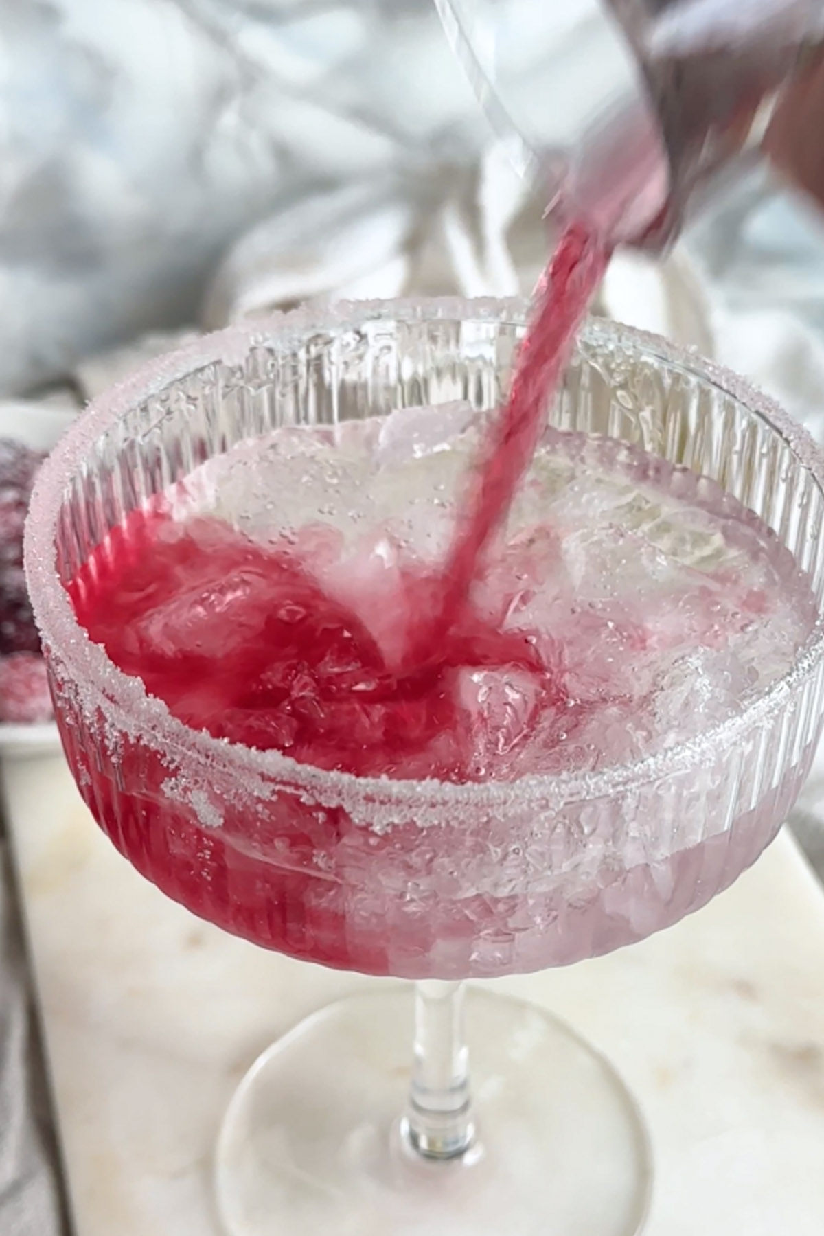 Cranberry juice is poured into a glass with ice.
