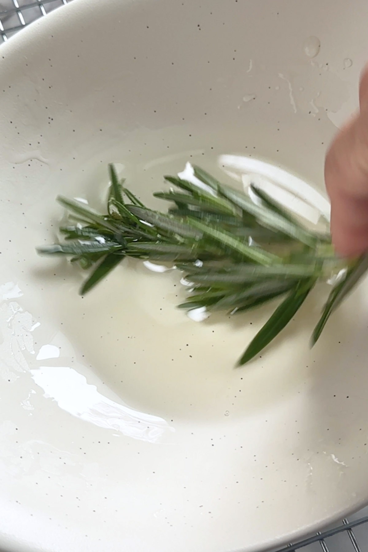Rosemary is dipped into simple syrup.