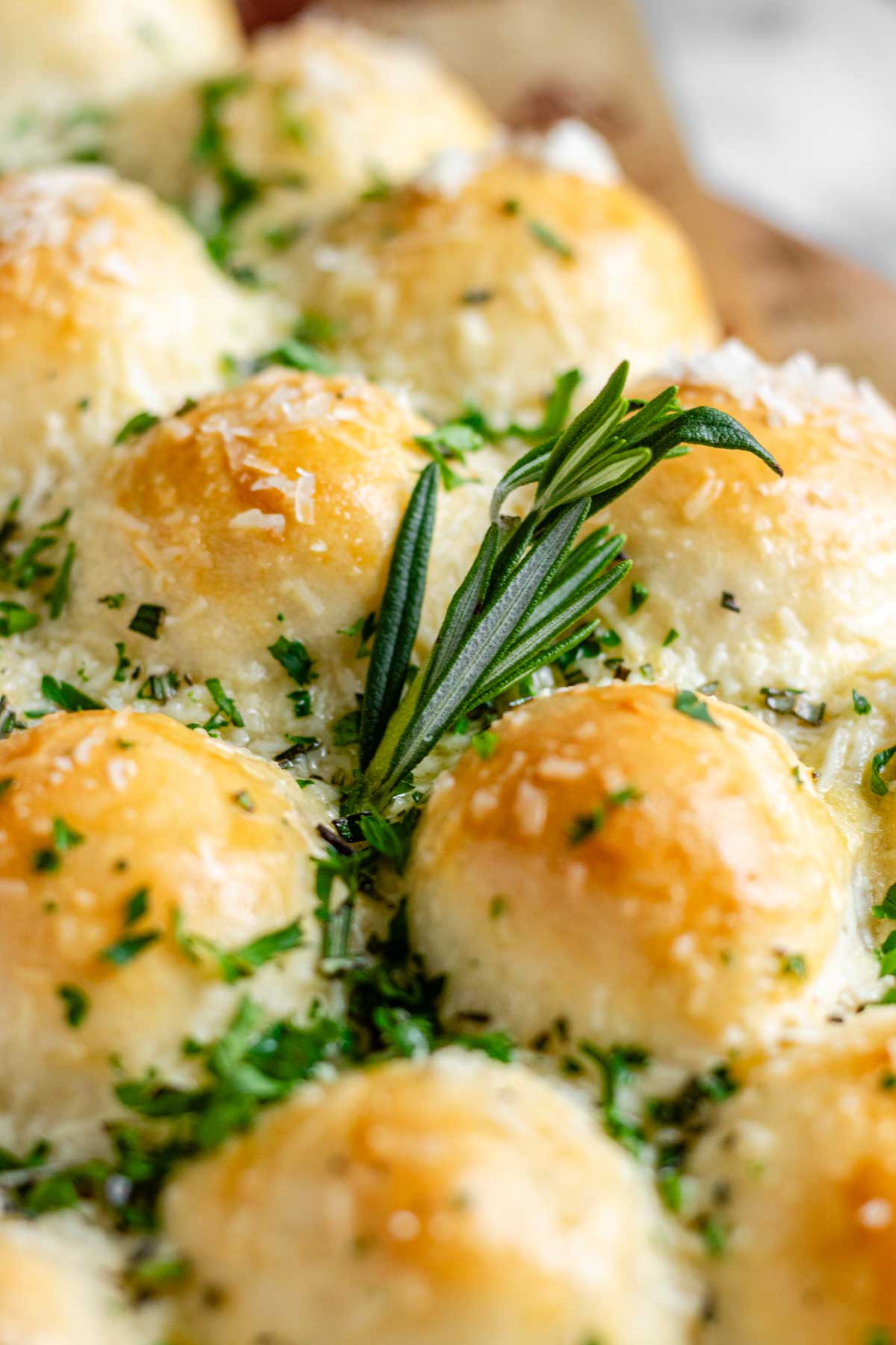 Close up of rolls of dough baked in the shape of a Christmas tree, garnished with cheese and fresh herbs.