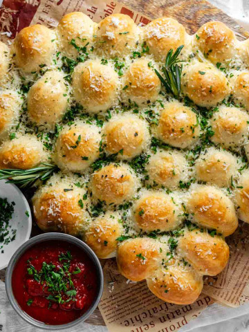 Rolls of dough baked in the shape of a Christmas tree, garnished with cheese and fresh herbs.