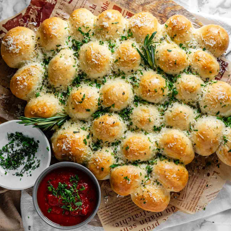 Rolls of dough baked in the shape of a Christmas tree, garnished with cheese and fresh herbs.