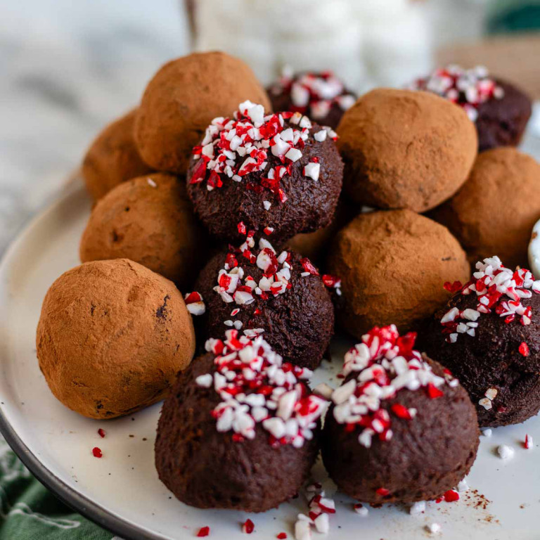 A plate of truffles, half coated in cocoa powder and half coated in crushed candy canes.