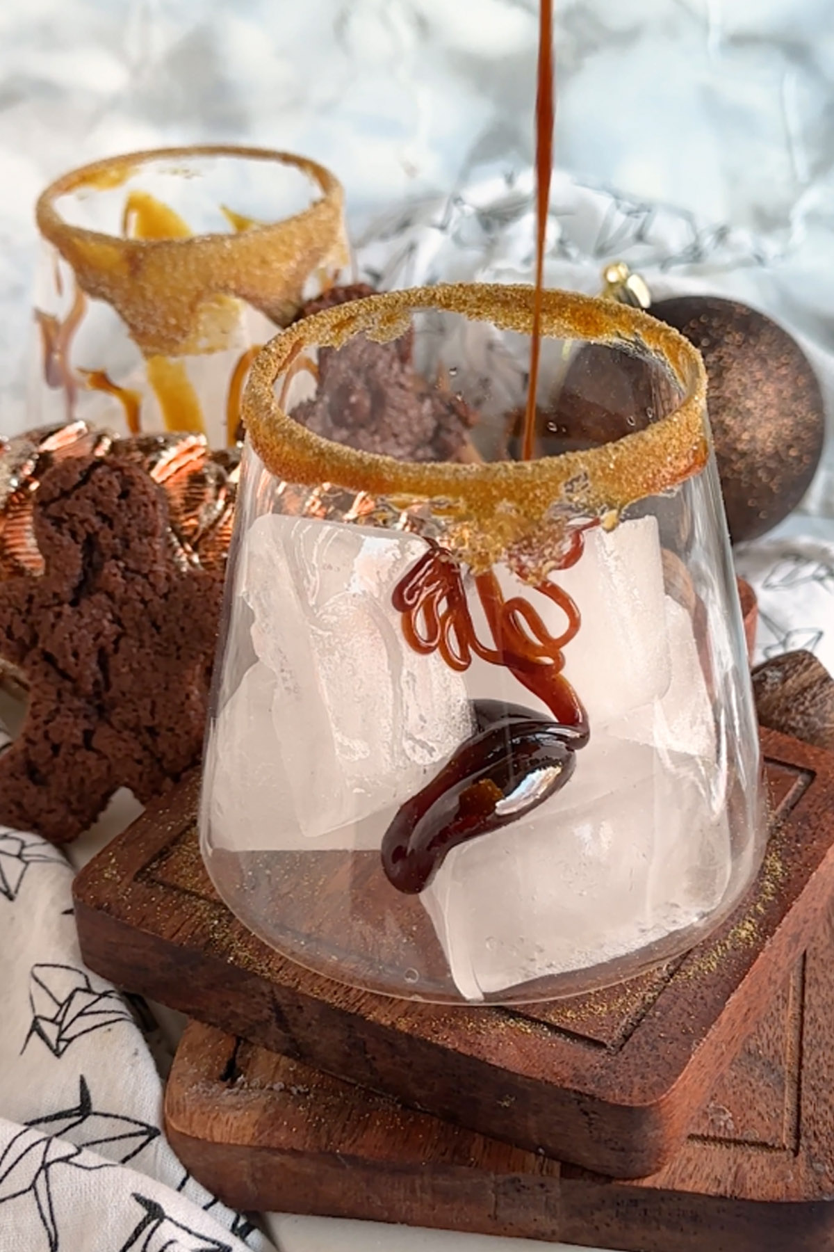 Gingerbread syrup is drizzled into a rimmed glass with ice.