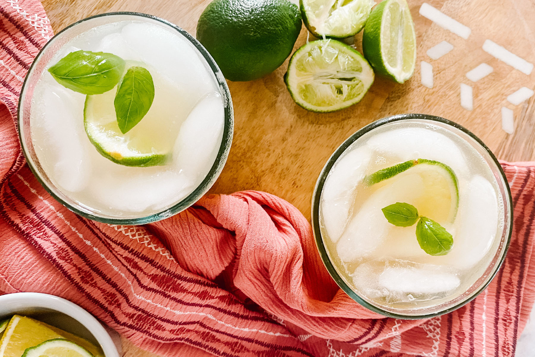 A cocktail in a glass garnished with lime and mint.