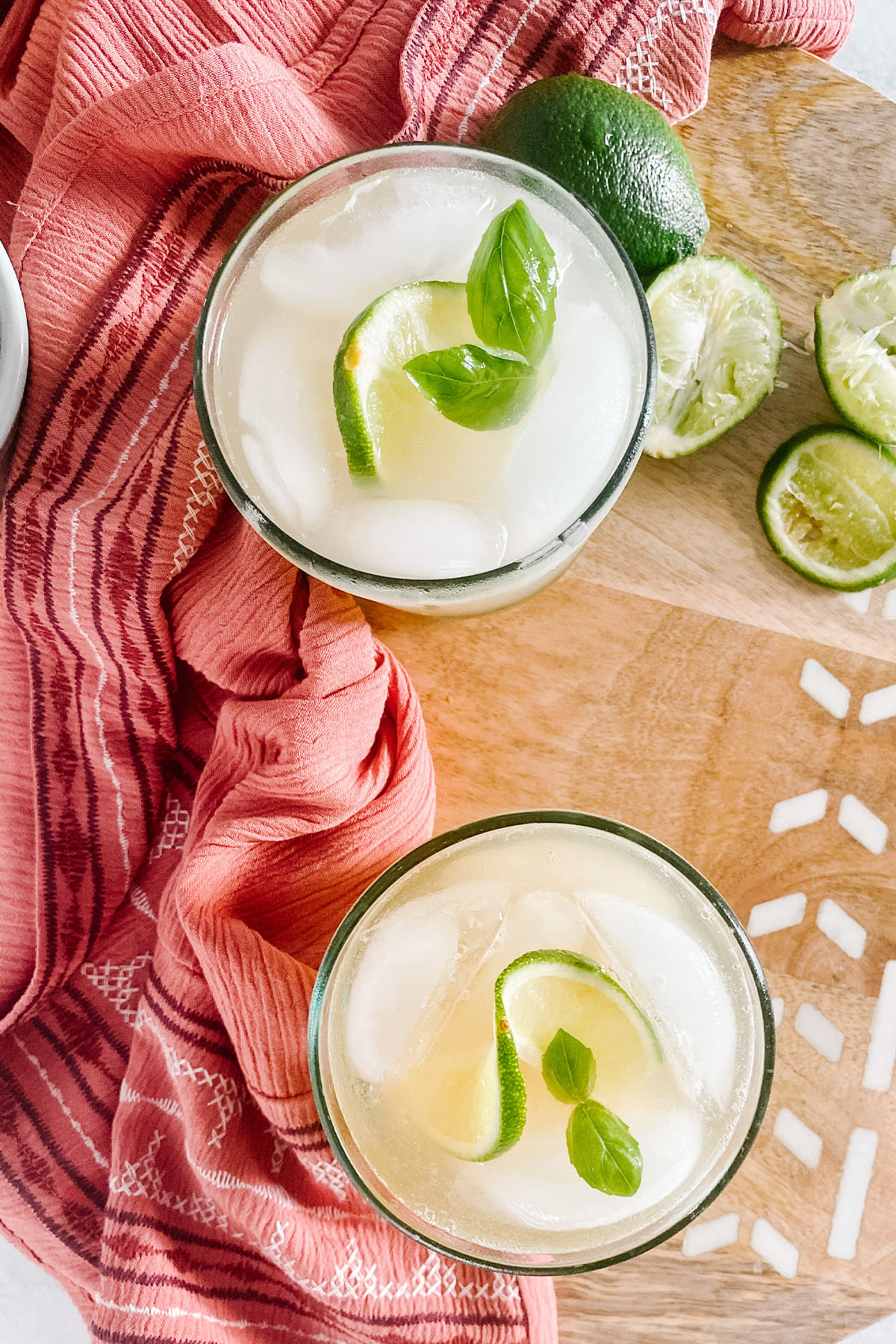 A cocktail in a glass garnished with lime and mint.