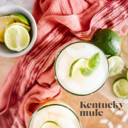 A cocktail in a glass garnished with lime and mint with text title for Pinterest.