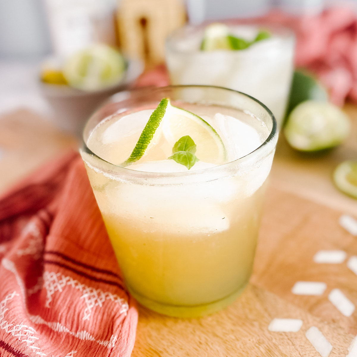 A cocktail in a glass garnished with lime and mint.