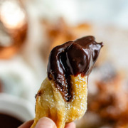 A piece of puff pastry with chocolate dip on it is held up by hand with text for Pinterest.