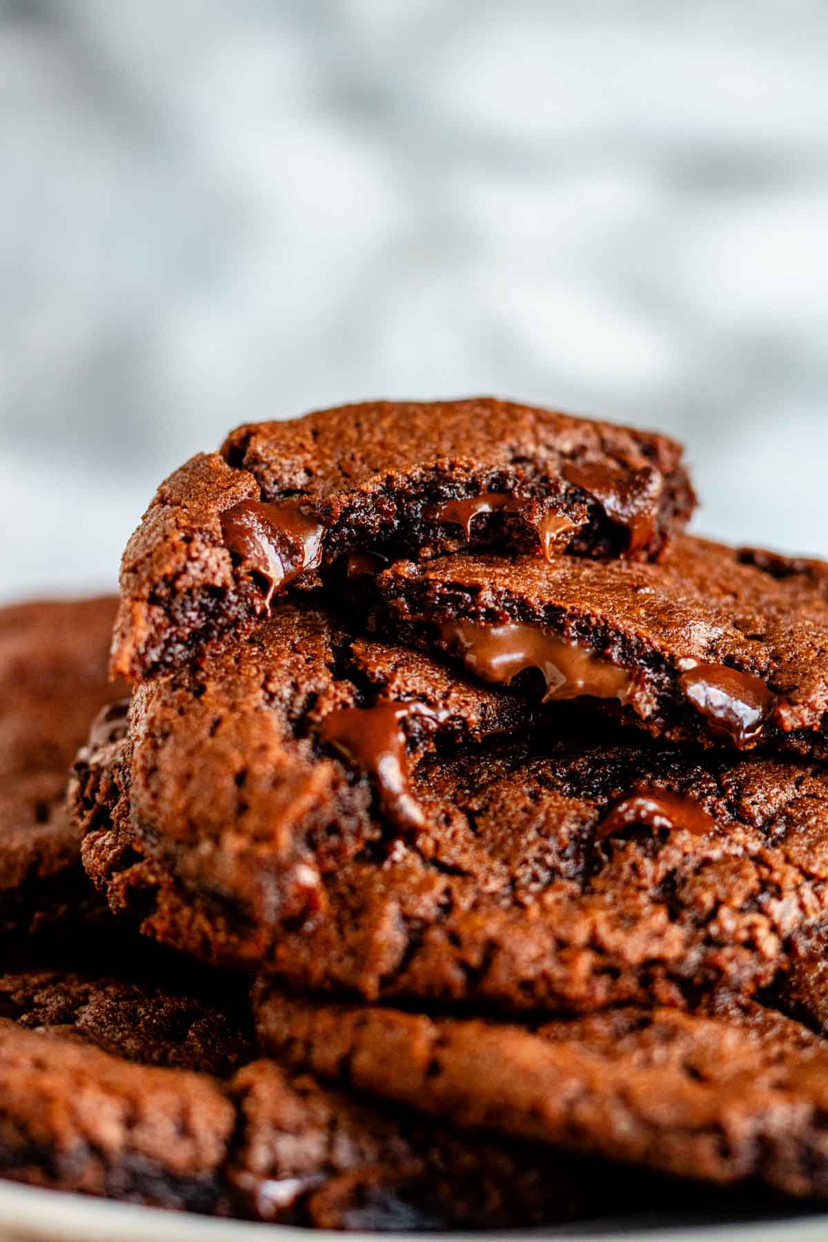 A plate of chocolate chocolate chip cookies with half cookies on the top and melted chocolate.