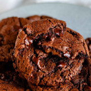 A plate of chocolate chocolate chip cookies with half cookies on the top and melted chocolate with text for Pinterest.