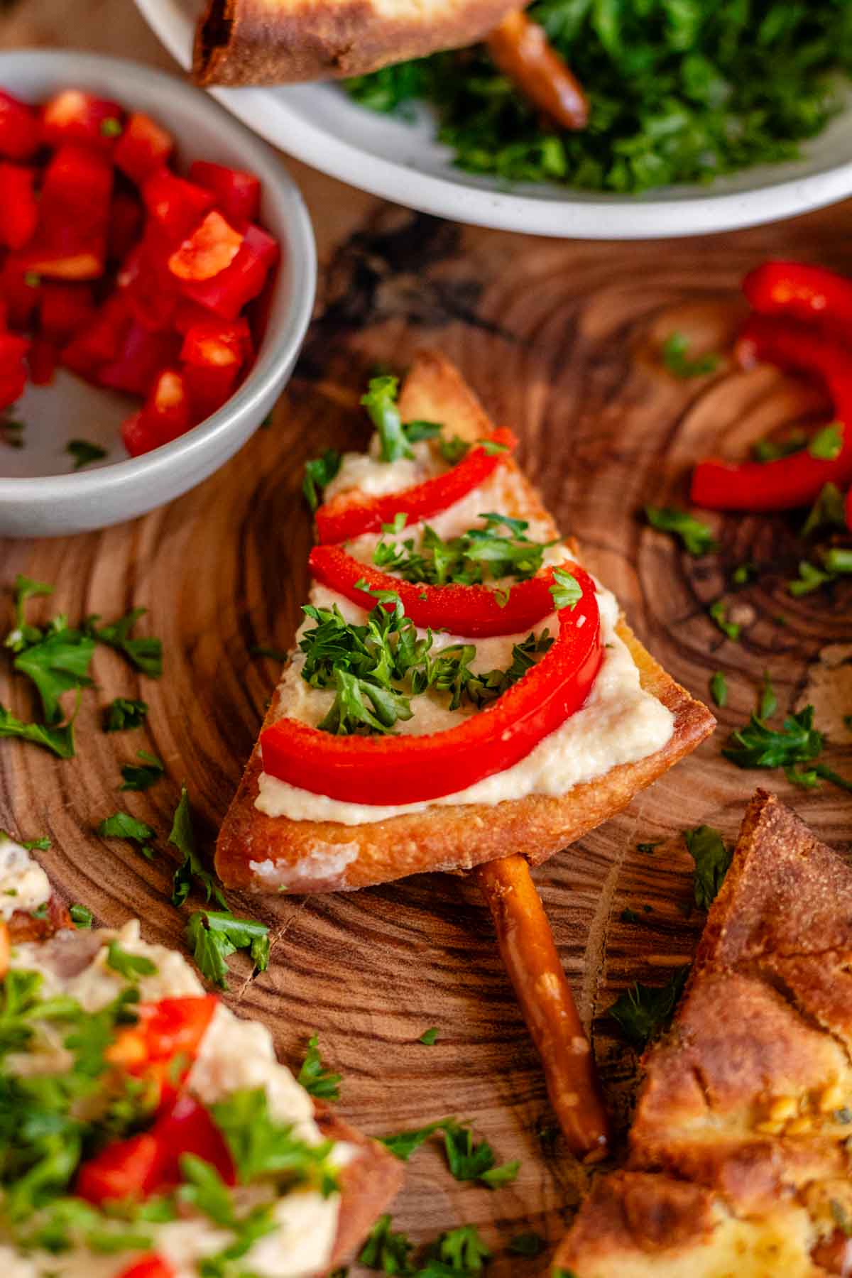 Pita chips decorated like Christmas trees with red pepper, parsley, and a pretzel as a trunk.